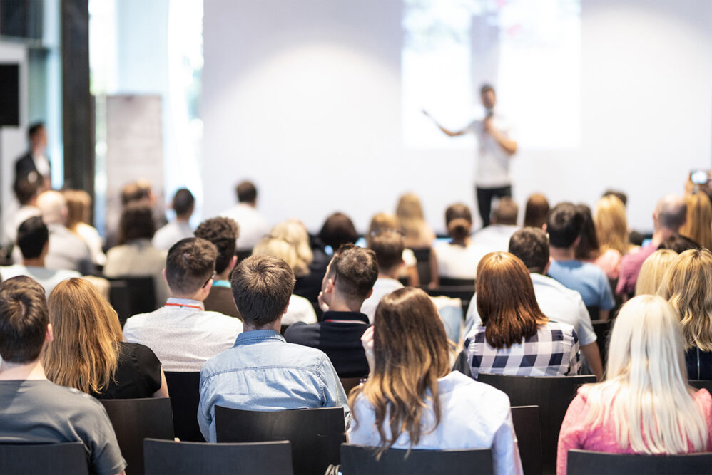 Photo of man media expert presenting in front of large audience