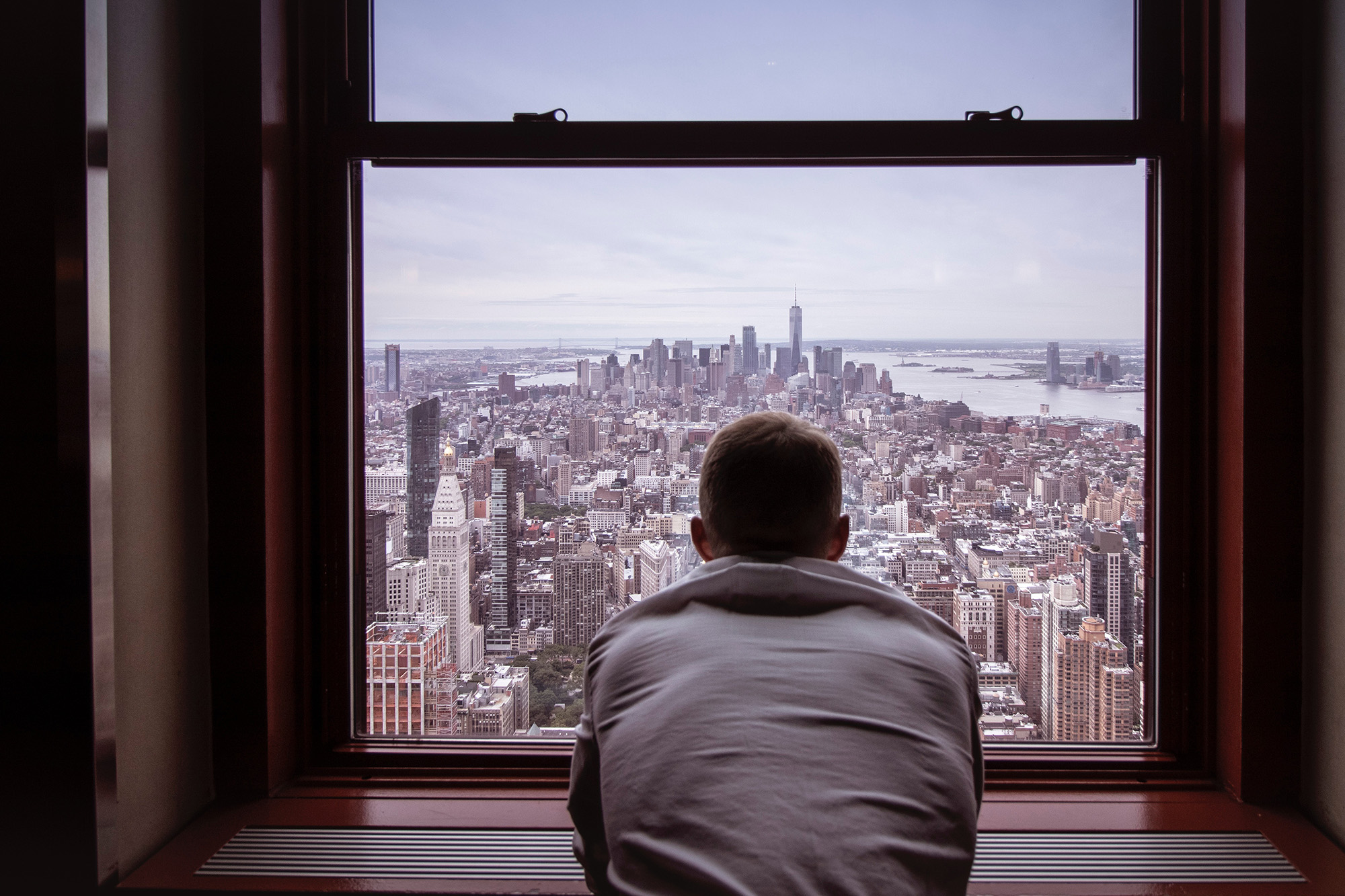 Photo of man leaning out window looking out over city skyline